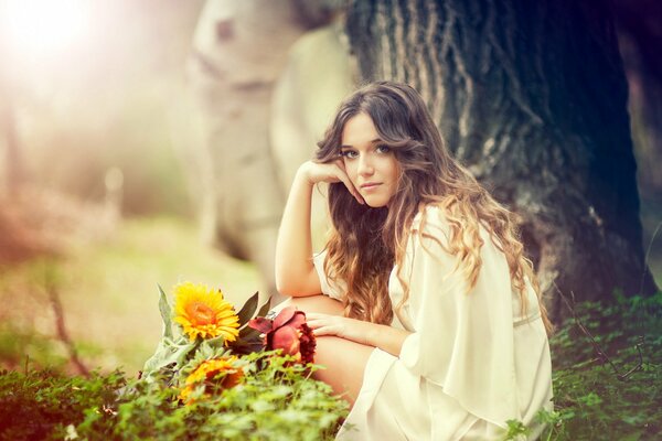 Lorena Bey sitzt mit Blumen im Wald 