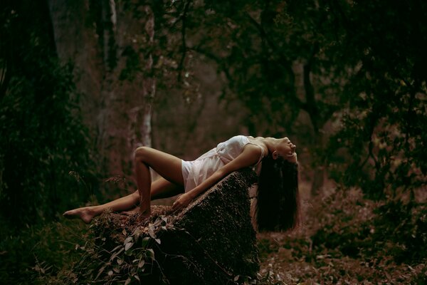 Foto eines Mädchens auf einem Stein im Wald