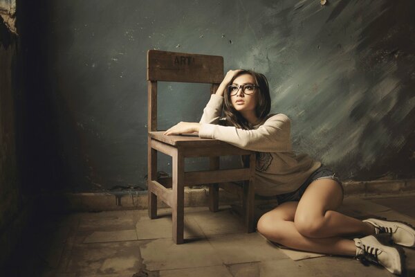 Zamyślona dziewczyna w okularach i krzesło