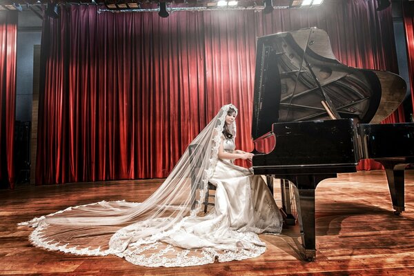 Asian girl in a wedding dress and veil plays the piano