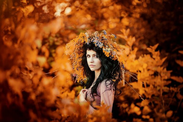 Retrato de otoño de una niña en una corona de hojas