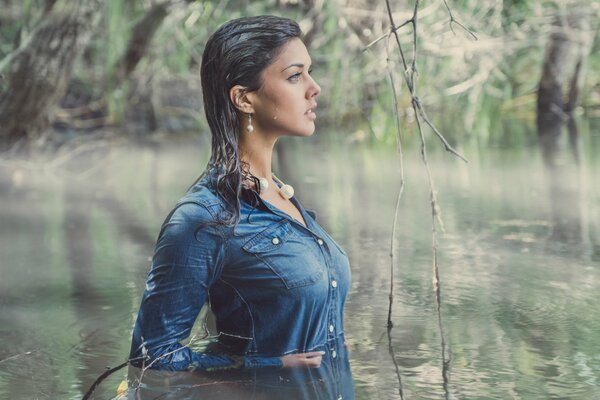 Ein Mädchen in einem blauen Kleid steht am Gürtel im Wasser