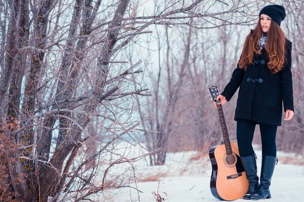 Ragazza con la chitarra nella foresta invernale