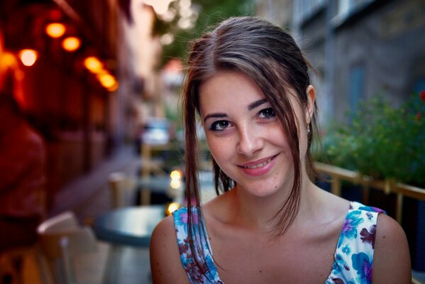 Cute brown-eyed girl smiles against the background of a cafe