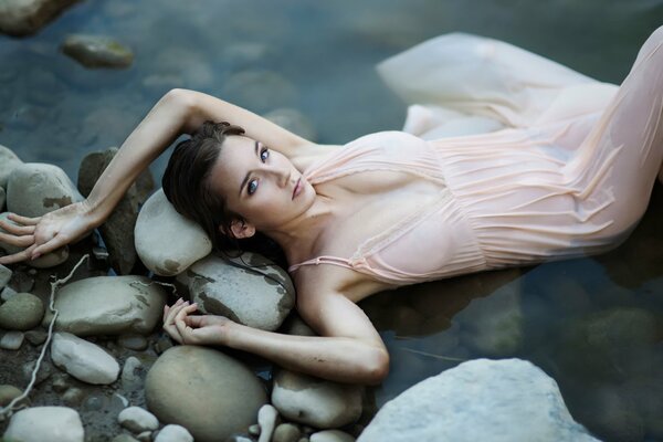 Chica mojada yace en las rocas