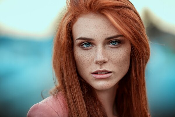 Retrato de una pelirroja, de ojos azules chica con pecas en la cara