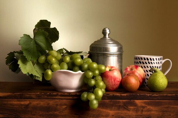 Nature morte avec des fruits et des raisins dans un vase sur une table