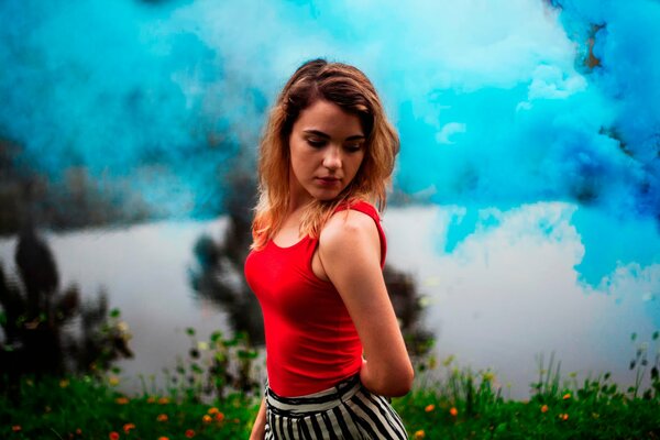 Ritratto di una ragazza in un top rosso su uno sfondo di fumo