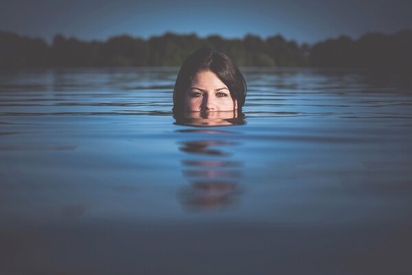 Fille aux cheveux noirs nage dans le lac