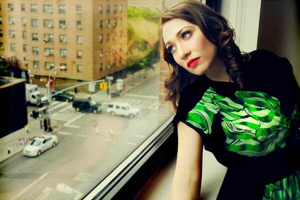 The girl looks out the window at the city