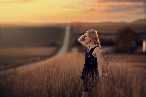 A girl looking into the distance against the background of the outgoing road