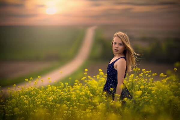 Mädchen im Feld an der Straße bei Sonnenuntergang