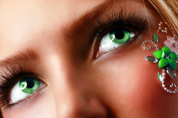 Rubia de ojos verdes con decoración de diamantes de imitación en la cara