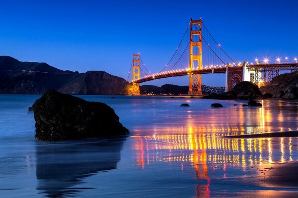 Nachtansicht der Golden Gate Bridge und ihre Reflexion im Wasser