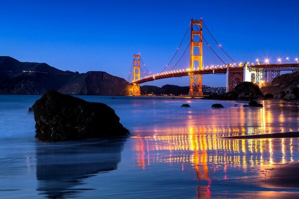 Vista nocturna del puente Golden Gate y su reflejo en el agua