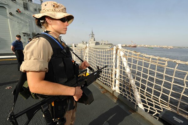 A girl soldier with a gun on board a ship