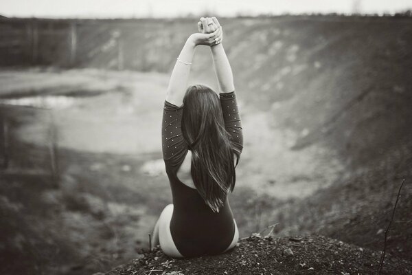 Photo en noir et blanc d une jeune fille à l arrière, assis sur le bord d une falaise