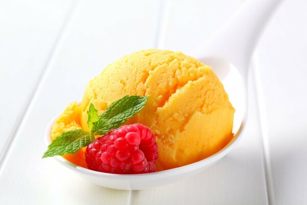 Yellow ice cream with raspberry and leaf