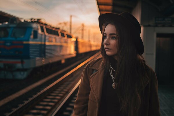 Mädchen mit schwarzem Hut am Bahnhof