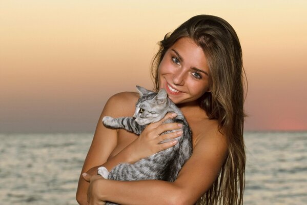 Chica sonriente de pelo largo con un gato en el fondo del mar