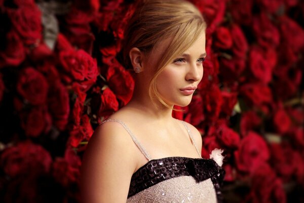 The actress is photographed against a background of red roses