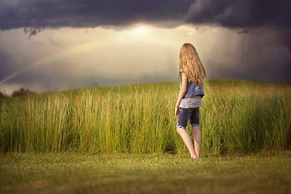 La ragazza nel campo guarda il cielo grigio