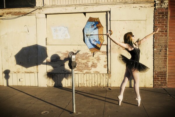 A ballerina girl on the street with an umbrella