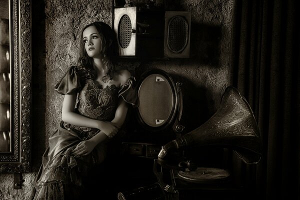 A girl in an antique dress listens to a gramophone