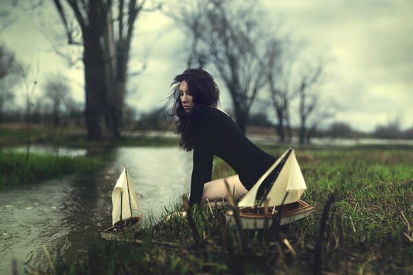 Dziewczyna w czarnej sukience wystrzeliwuje łodzie po rzece