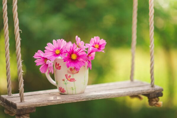 Tazza con un mazzo di fiori su un altalena per bambini