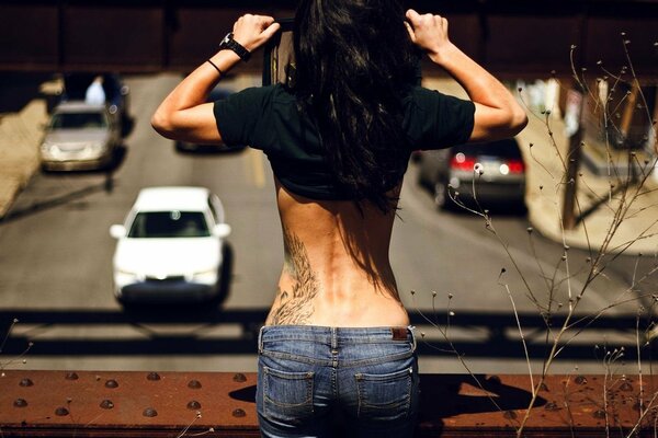 Mädchen mit Tattoos auf dem Rücken auf der Brücke