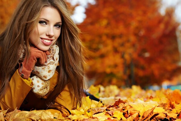 Bella ragazza sorridente. Giovane ragazza sullo sfondo del paesaggio autunnale. Ragazza sdraiata sulle foglie d autunno dorate