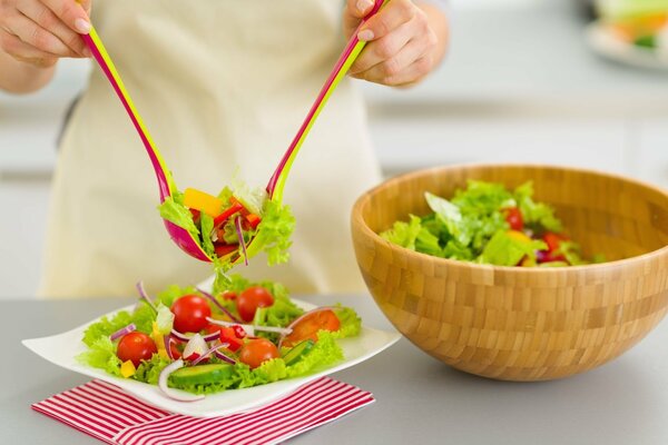 Hands put green salad on a plate