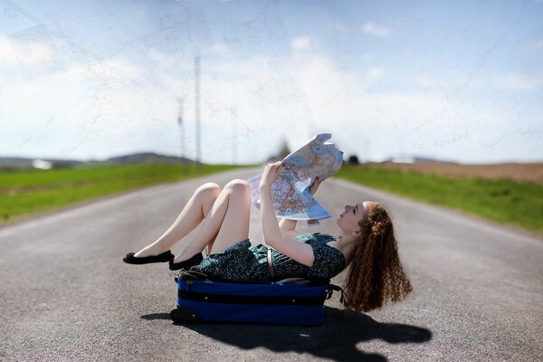 The girl is lying on the road and looking at a geographical map