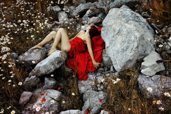 Professional photo of a model girl in a red dress. In a red dress on a background of stones