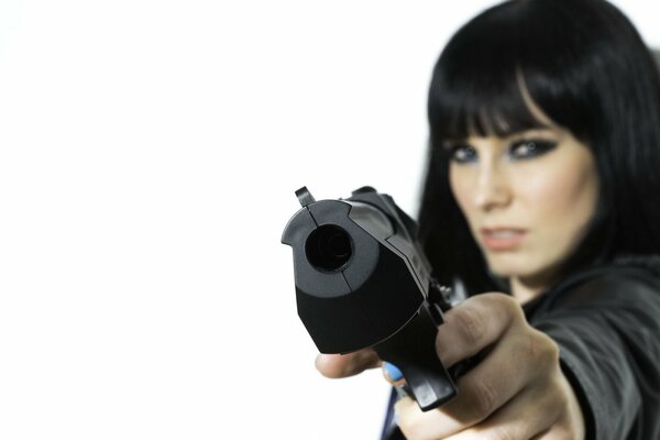 Staged photo of a girl with a gun. The girl aims at the camera