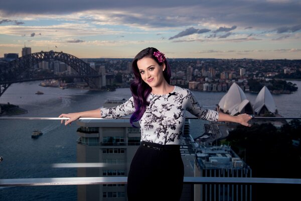 Il sorriso di Katy Perry con i capelli viola sullo sfondo della città