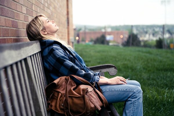 Fille sur le banc de repos réflexion mur de briques