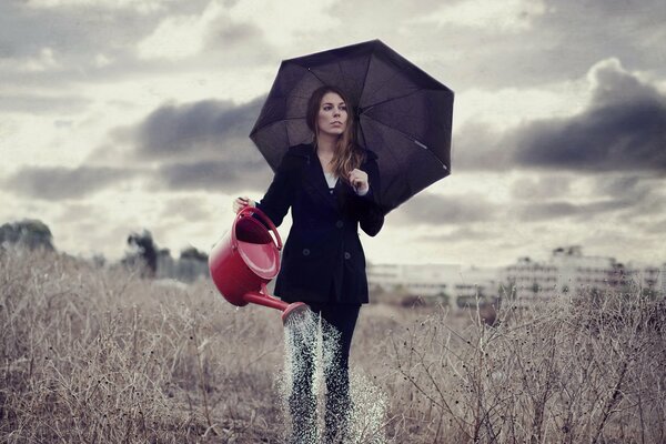 Fille sous le parapluie arrose de l arrosoir