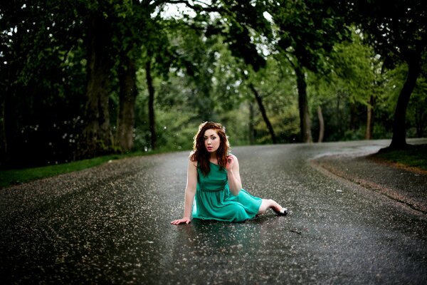 Fille assise sous la pluie sur la route