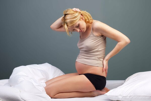 Schwangere Blondine sitzt im Bett