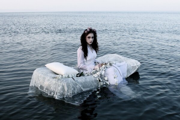 Fotoshooting am Fluss im Bett. Mädchen im weißen Kleid