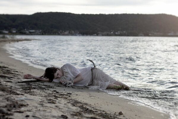 The girl is lying on the sand by the sea