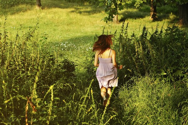 A girl running through a green, sunlit field