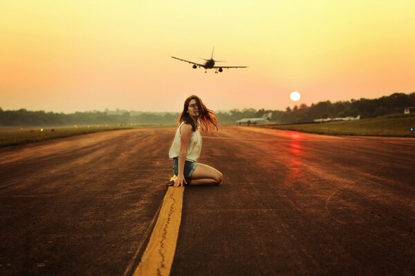 A brown-haired slender girl is sitting on the road