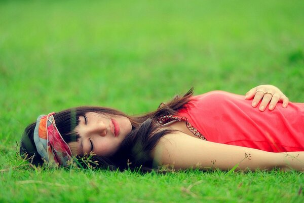 Asian woman lies on the grass with her eyes closed