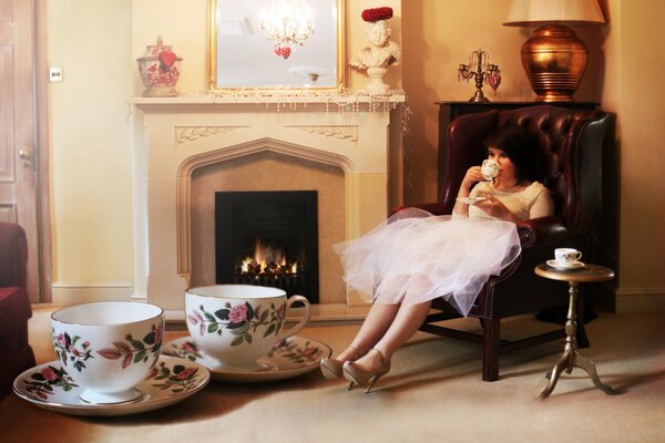 Fille de thé en robe, avec des tasses