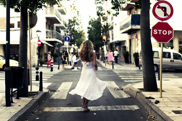 Ragazza in abito bianco cammina per la città