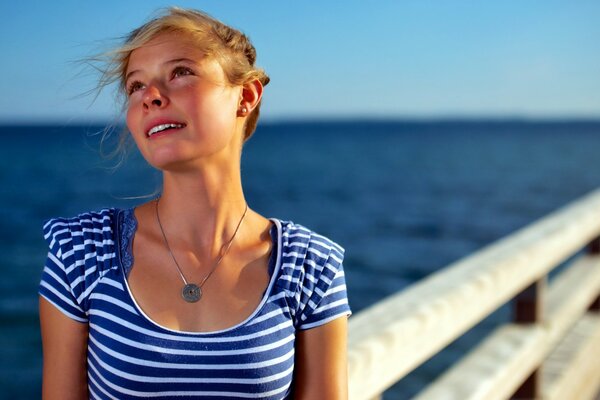 Fille rêveuse dans un t-shirt près de la mer