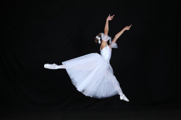 Ballerine de saut en robe blanche sur fond noir